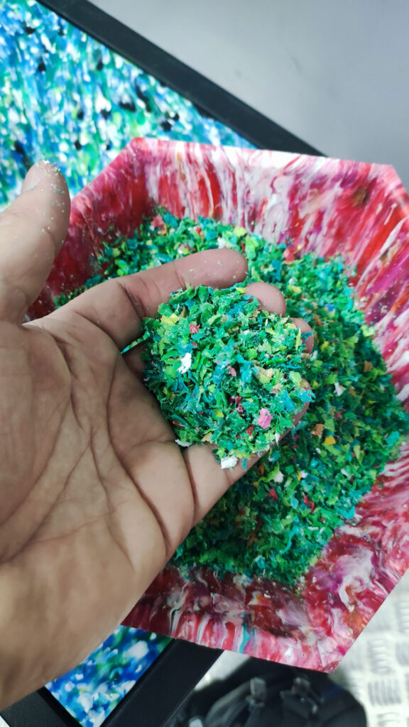 Крошка из переработанных пластиковых крышек в руке