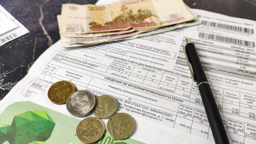 Квитанция за коммунальные услуги, деньги и ручка на столе